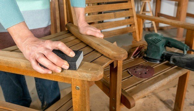 Woman grinds off chair with sandpaper - whiten wooden furniture